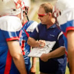 Football coach going over play to football players.