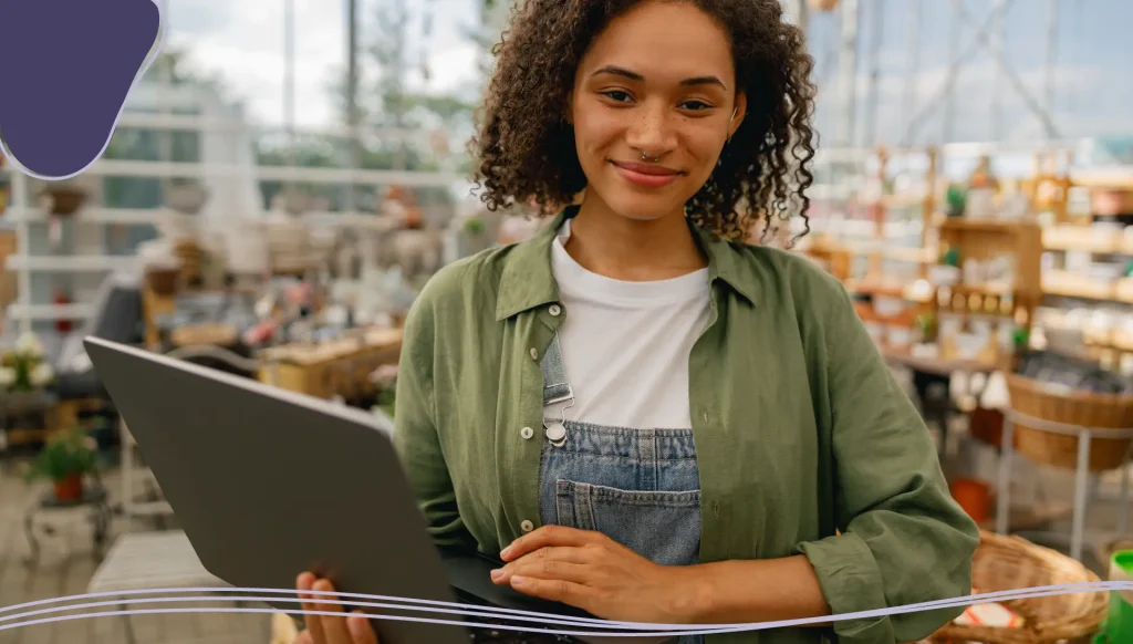 Female gardening shop owner working on laptop on garden store center background.