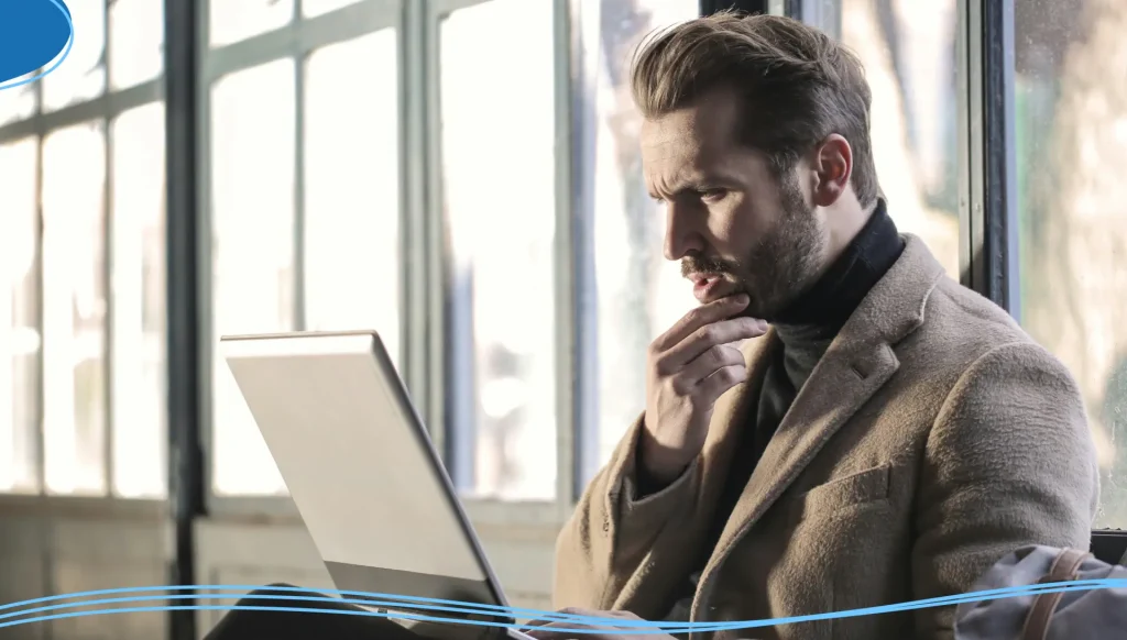 A man holding his chin facing laptop computer.