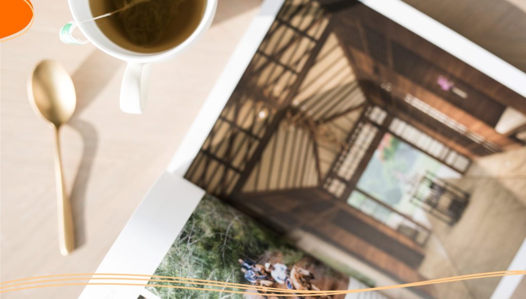 Brochure open on a table with a spoon and cup of tea