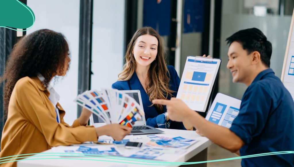 Three people sitting around a desk looking at marketing materials and brochures