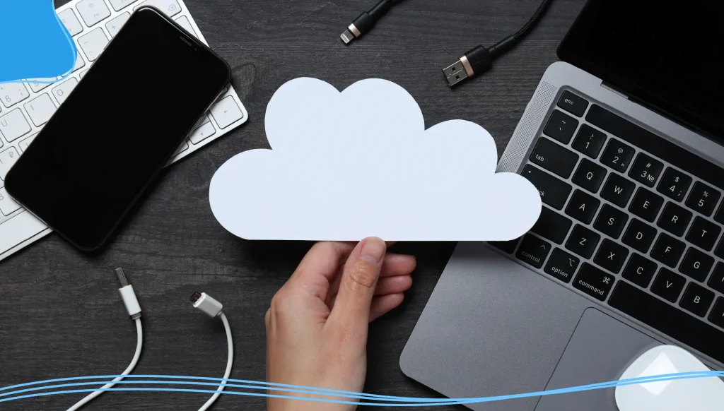 White, paper cloud with various gadgets on a black table background.