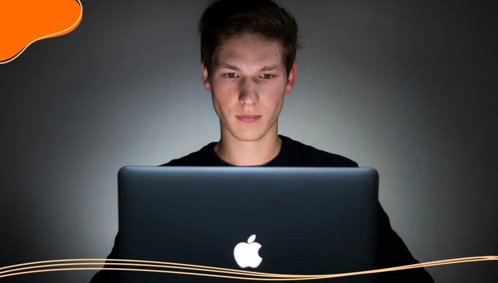 A young man staring at an animated logo on a laptop computer