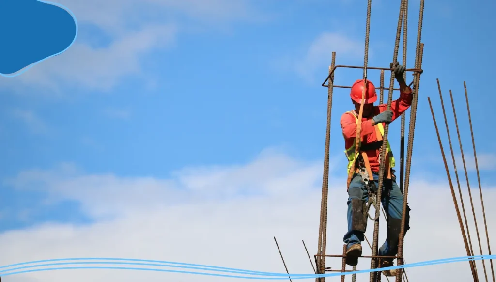 A construction worker climbs a wire frame on a construction site.