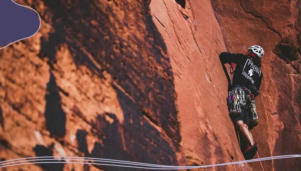 A climber makes their way up a steep cliff face.